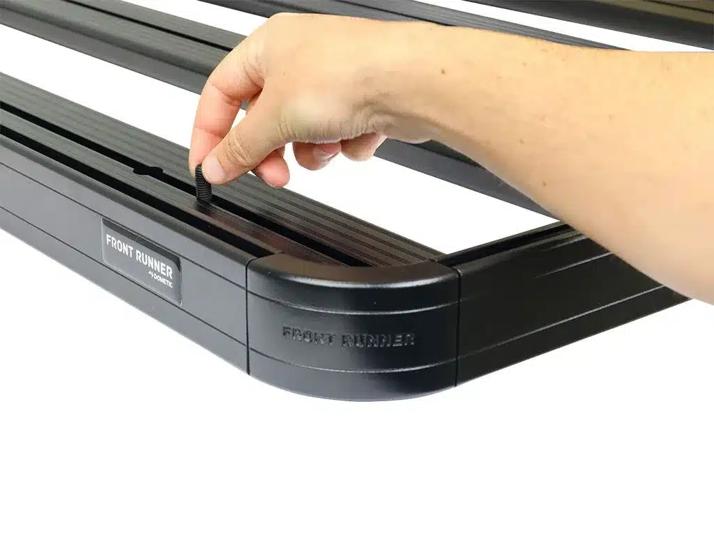 krsj007t_gen_2_ – Wolf Customs | 4x4 Accessories and Fitment Person's hand inserts a small plug into a Front Runner gym/rack accessory edge, tightening it into place